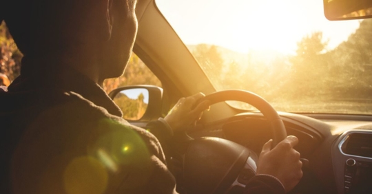young man driving in summer sun